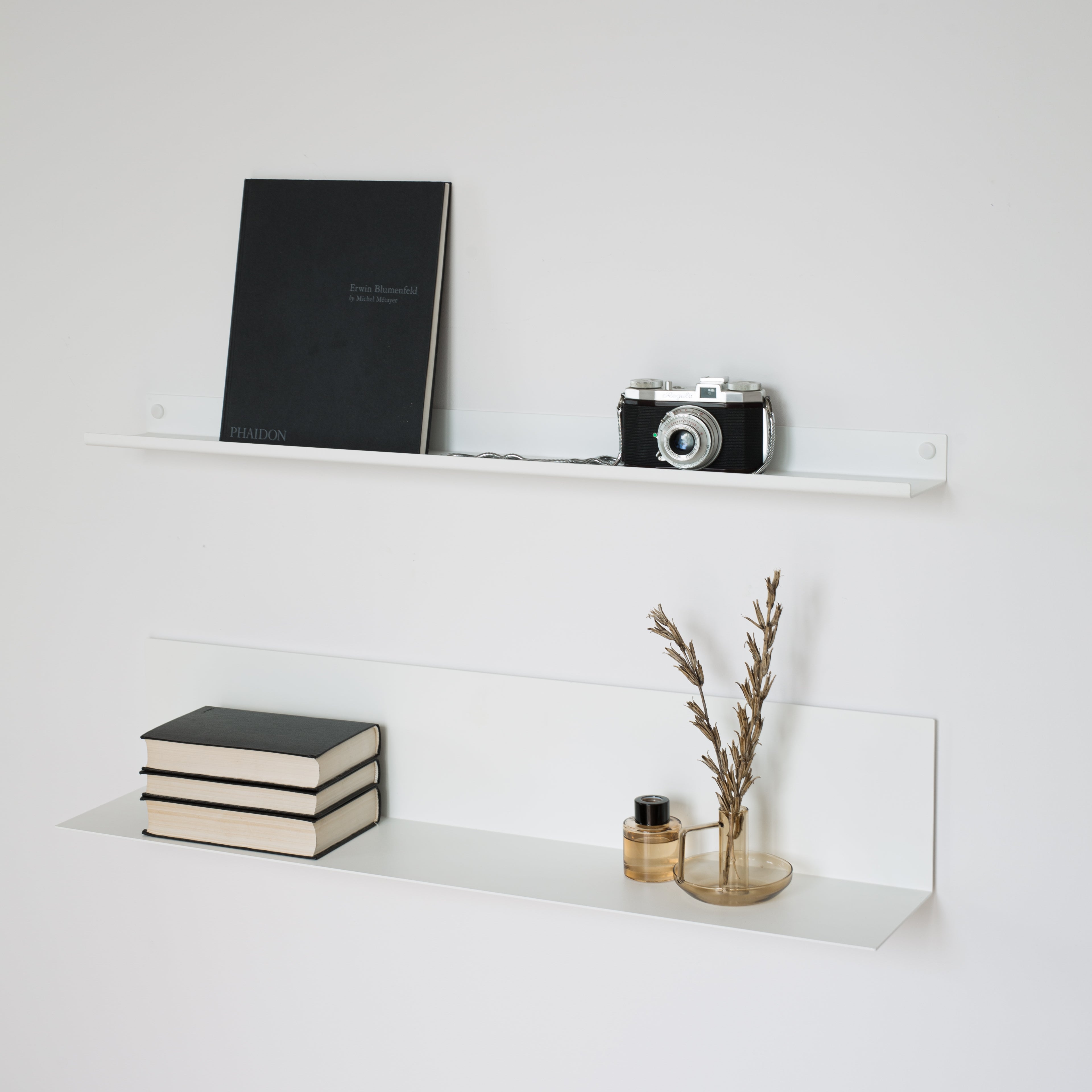 large and narrow modern white shelves holding books and decoration on white wall