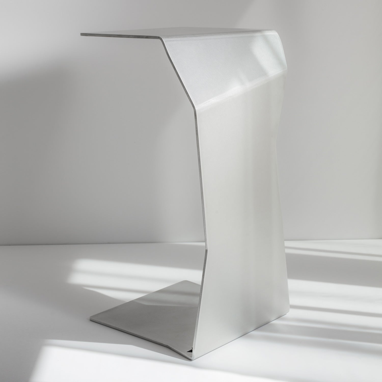 RAW finish metal side table on neutral plain background