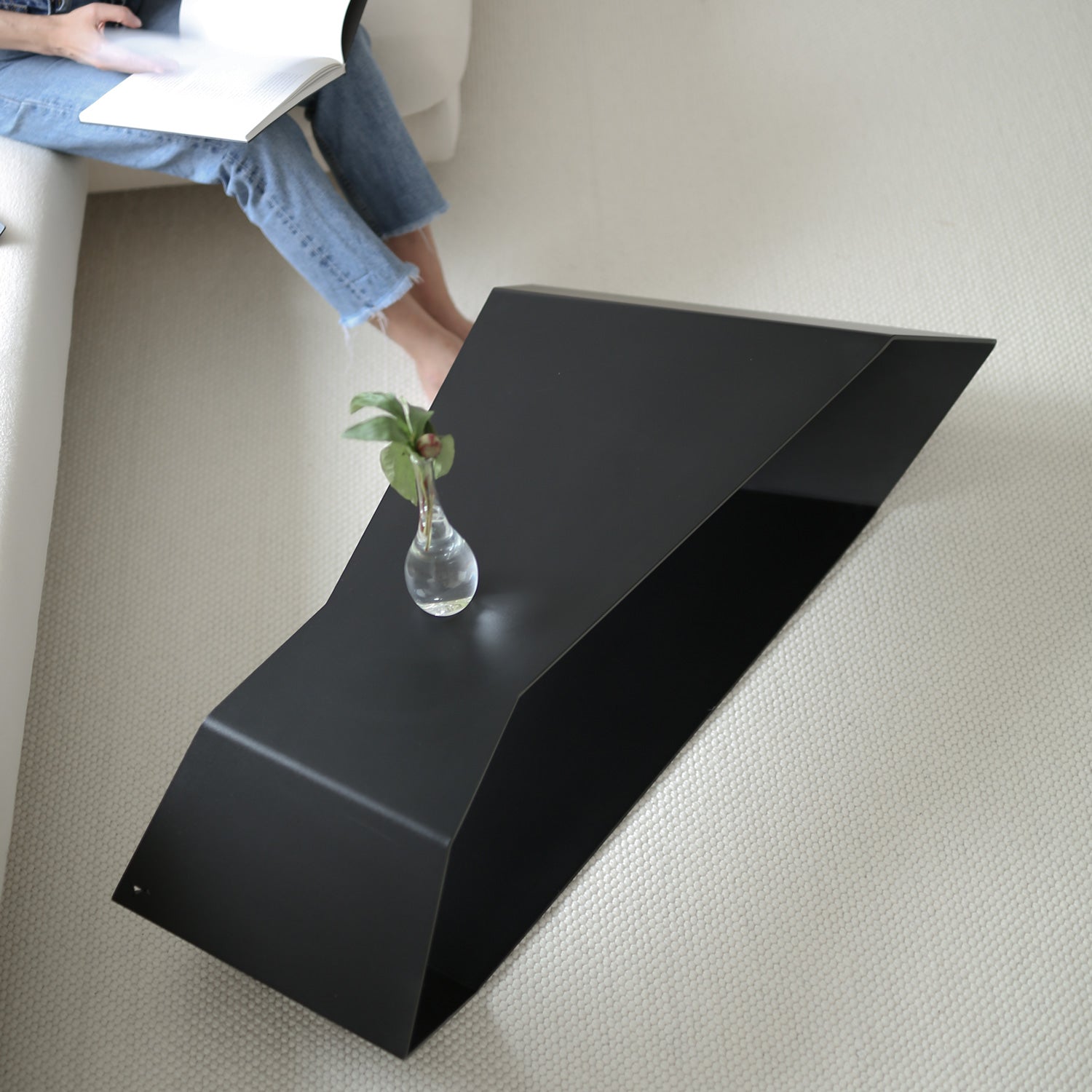 Black large coffee table in upside-down setup with girl reading nearby
